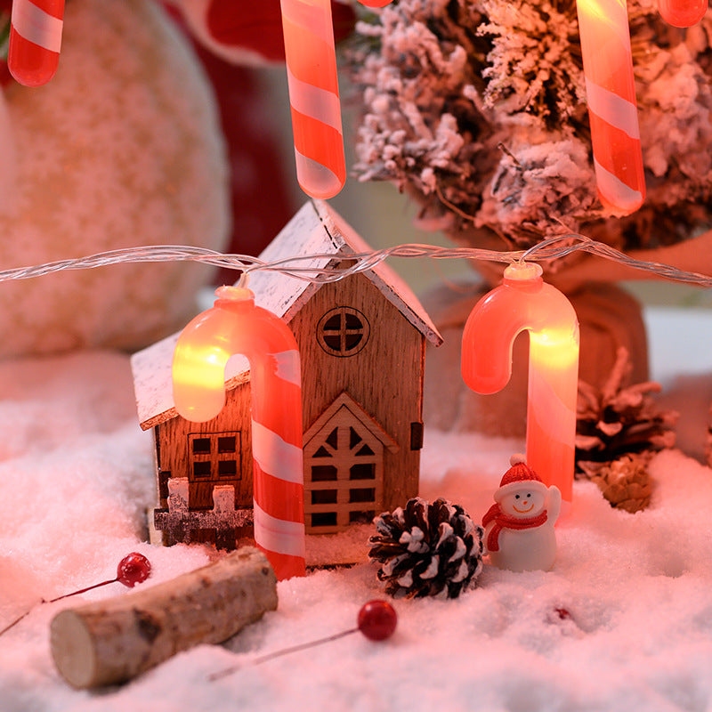 Christmas-themed decoration with candy canes, a small house, and lights on a snowy background.