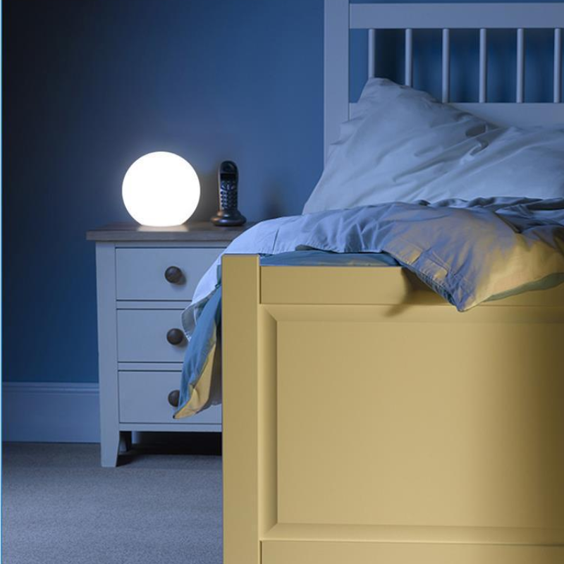 Bedroom with a nightstand featuring a Modern LED Orb Lights Outdoor and a bed with blue bedding.