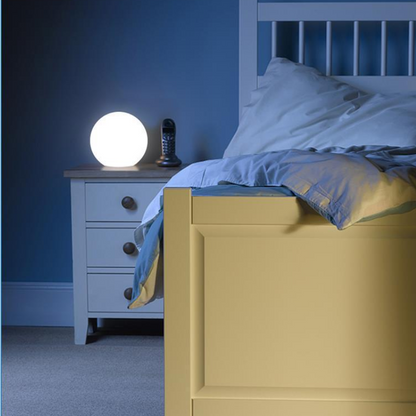 Bedroom with a nightstand featuring a Modern LED Orb Lights Outdoor and a bed with blue bedding.