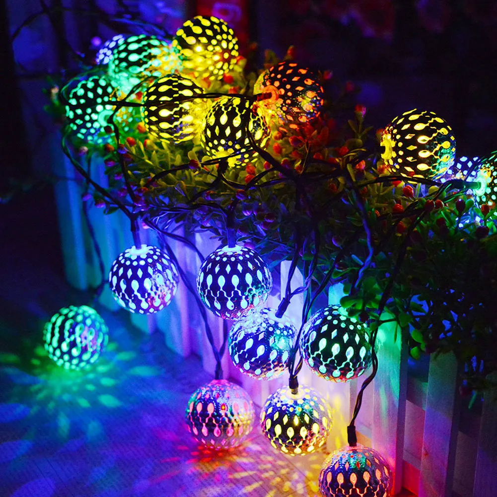 Colorful Moroccan Metal Ball LED String Lights with decorative bulbs on a branch against a dark background