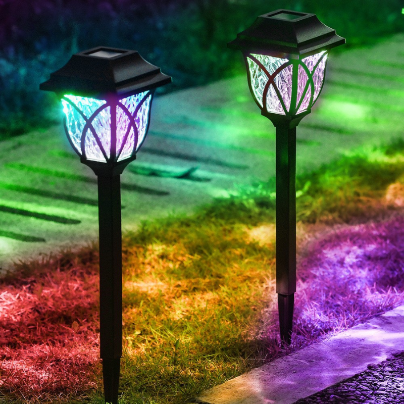 Two Outdoor Solar Garden Path Lights emitting colorful light on a grassy path.