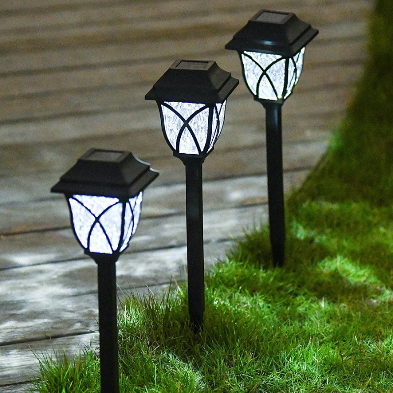 Three Outdoor Solar Garden Path Lights on grass next to a wooden deck.