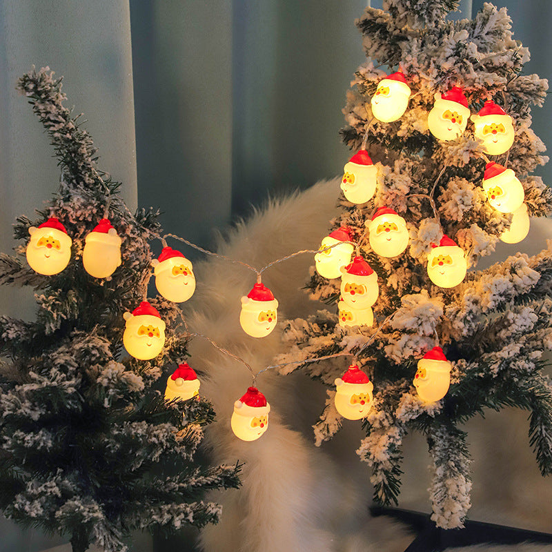 Decorative string lights shaped like Santa Claus on a Christmas tree.