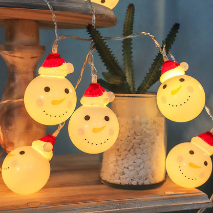 Santa Claus LED String Lights with snowman design on a wooden surface with a plant in the background