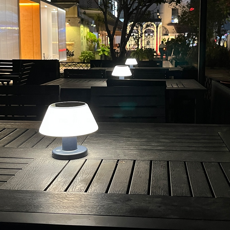 Solar Table Lamp Outdoor on a wooden table with a blurred background of a restaurant.