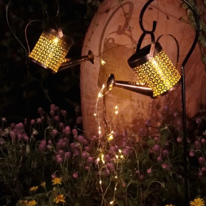 Solar Watering Can Garden Light with string lights on a garden background.