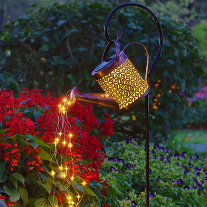 Solar Watering Can Garden Light with string lights in a garden setting