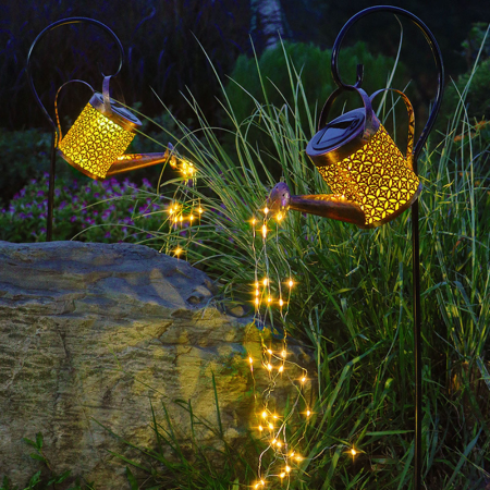 Solar Watering Can Garden Light with string lights in a garden setting